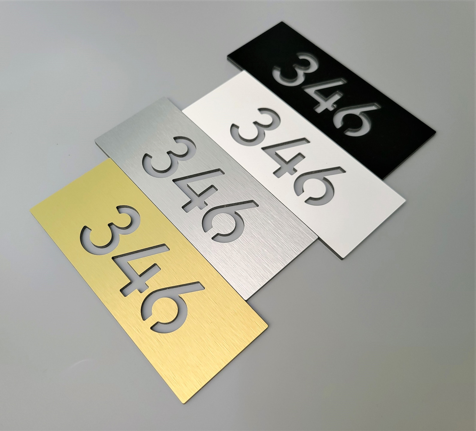 Sample set showing several unit number styles — brushed metal, painted aluminum, and brass.