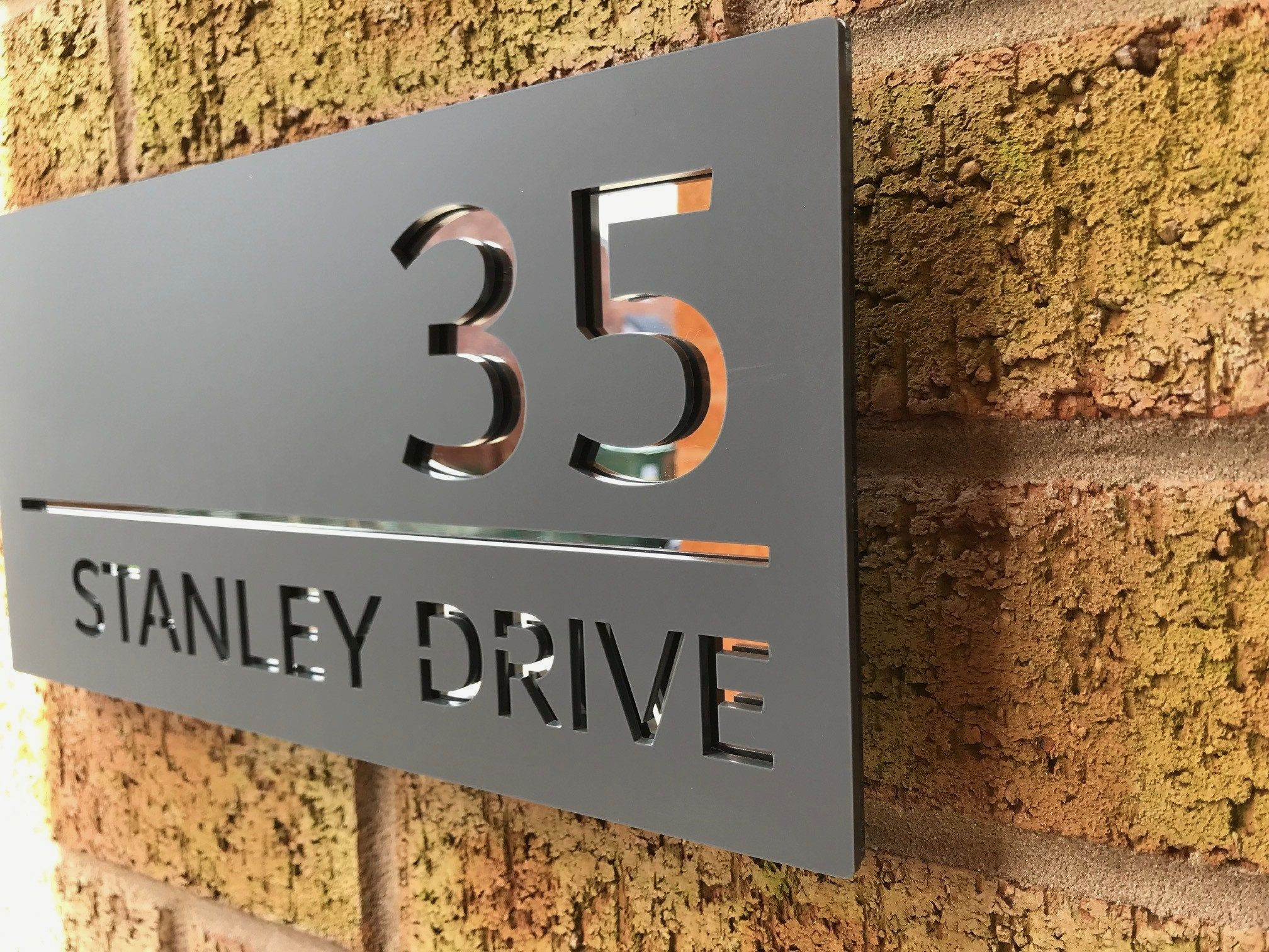 35 Stanley Drive in brushed stainless with backlight with standoff mounting to brick