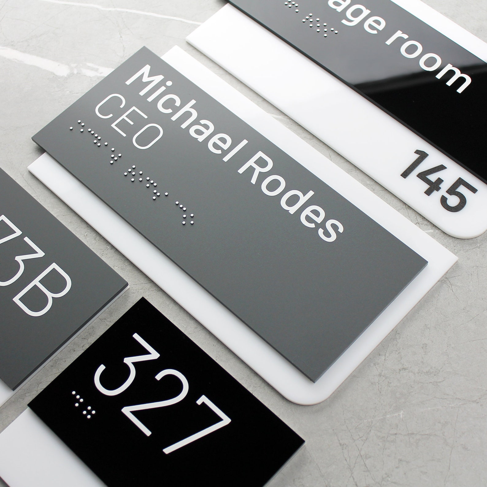 ADA-compliant suite signs with photopolymer raised copy and Grade II Braille, in solid-surface material.